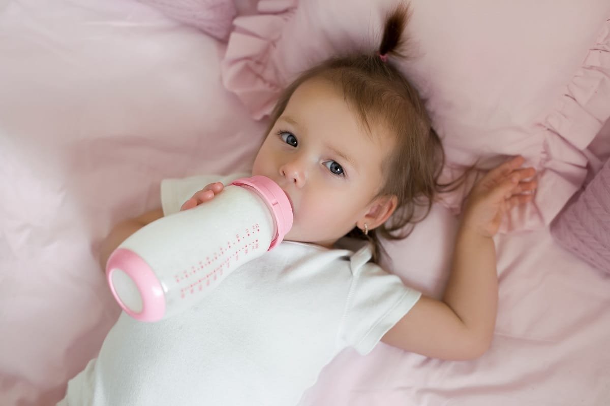 il bambino sta bevendo il latte da una bottiglia.  un'alimentazione sana ed equilibrata per i bambini è la chiave per la salute del bambino.  il latte artificiale è ricco di vitamine importanti per la crescita e lo sviluppo del bambino